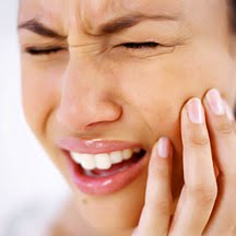 Front view of young woman holding her cheek in pain